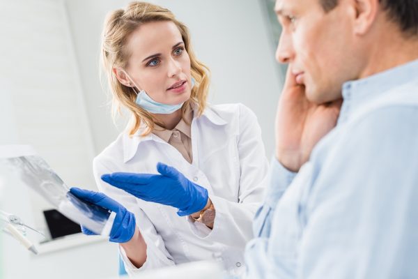 Man consulting with dentist looking at x-ray in modern clinic